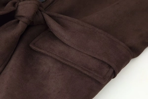 Detail of dark brown faux suede coat featuring a pocket flap and waist tie belt texture