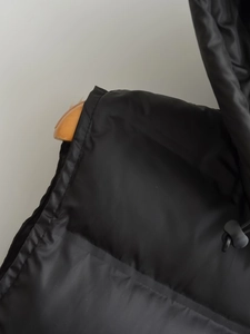 Detailaufnahme der schwarzen gesteppten Pufferweste mit Kordelzug und Textur
