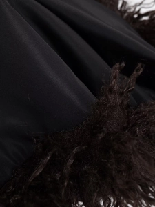 Detail shot of smooth black fabric with contrasting dark brown curly faux fur trim texture