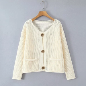 Dettaglio del cardigan in maglia traforata bianco crema con bottoni marroni e tasche