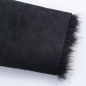 Detailed macro view of black faux suede texture and fluffy faux fur trim on winter coat