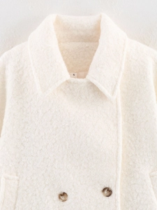 Detail of off-white faux shearling jacket with marble-textured brown buttons and lapel