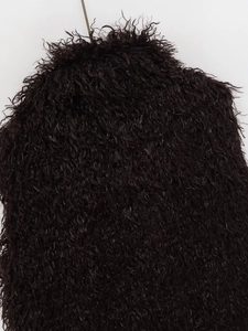 Close-up of black faux fur texture on a cropped vest showing curly long plush material