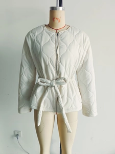 Detail of white quilted jacket featuring rounded diamond stitching and adjustable waist belt