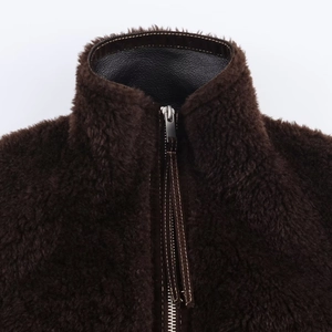 Detail of dark brown faux fur jacket with high collar and black leather lining accents