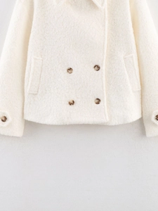 Detailed view of white bouclé coat featuring amber buttons and textured curly fleece