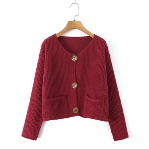 Dettaglio del cardigan in maglia bordeaux con bottoni dorati a rilievo e tasche applicate