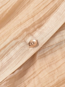 Détail du tissu plissé champagne avec un bouton en métal doré rose élégant et chic
