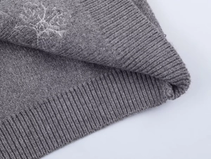 Detailed macro view of dark grey ribbed knit fabric with white snowflake embroidery