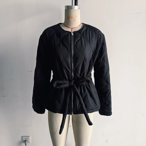 Detail of black quilted jacket featuring a metal zipper and large waist drawstring bow