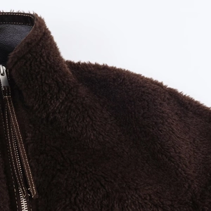 Detail of dark brown faux fur jacket showing stand collar and premium zipper with leather trim