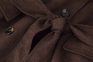 Detail of dark brown suede coat showing the waist tie, marble button, and pocket flap