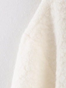 Detailed macro view showing soft white boucle faux fur texture of the winter coat fabric