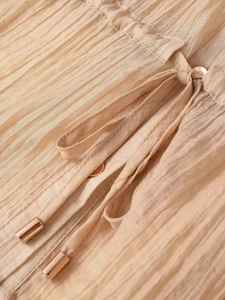 Détail du tissu plissé champagne avec cordon de serrage, embouts dorés et bouton assorti