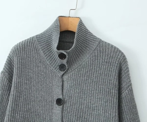 Detalle de cárdigan gris con cuello cisne, botones negros mate y textura de punto densa