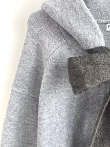 Close-up of gray hooded knit jacket featuring a dark gray bow detail and soft texture