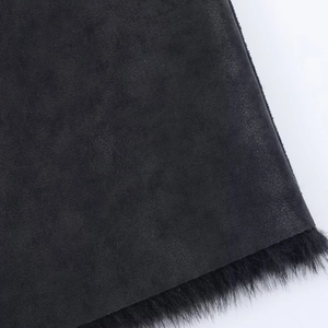 Close-up of black faux fur hem and matte suede texture on long winter coat details