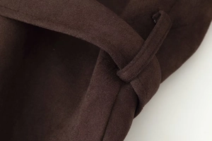 Close-up detail of belt loop and high-quality stitching on dark brown suede jacket