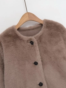 Close-up of light brown faux fur jacket with round neck and black buttons