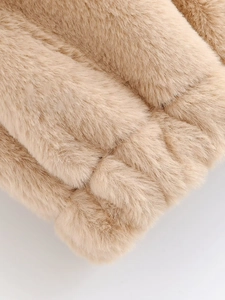 Gros plan sur le gilet en fausse fourrure beige montrant la texture douce et rayée