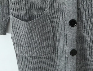 Detalle del cárdigan gris de punto acanalado con botones negros grandes y bolsillo texturizado