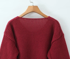 Dettaglio del cardigan in maglia bordeaux con trama a rete e bottoni decorativi