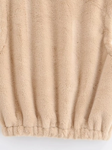 Gros plan sur la texture en fausse fourrure et l'ourlet élastique d'un gilet beige