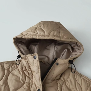 Close-up of khaki quilted hooded jacket with black metal buttons and drawstring detail