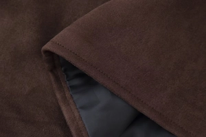 Macro shot of dark brown faux suede fabric showing smooth lining and fine stitching