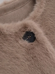 Detailed close-up of soft brown faux fur texture and black button on the jacket