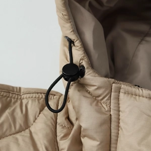 Close-up of khaki quilted jacket hood with adjustable black drawstring and round buckle