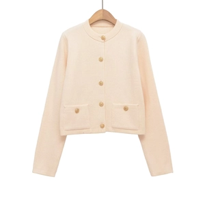 Close-up of elegant gold embossed buttons and pocket detail on beige knit cardigan