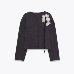 Detail der dunkelgrauen Strickjacke mit 3D-Stoffblumen in Weiß und schwarzen Schleifen
