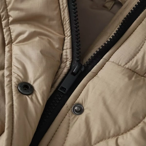 Detail of khaki quilted coat with ripstop fabric, resin zipper and metal snap buttons