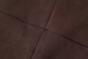 Macro shot of dark brown faux suede fabric with precise cross-stitch sewing details