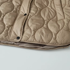 Close-up of onion quilting pattern and black metal snap buttons on khaki jacket