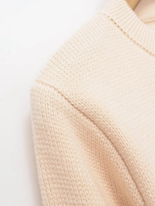 Macro detail of creamy knit cardigan showing fine texture and ribbed neckline seam