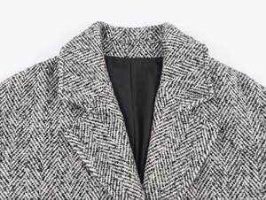 Close-up of black and white herringbone wool coat lapel with premium woven fabric texture