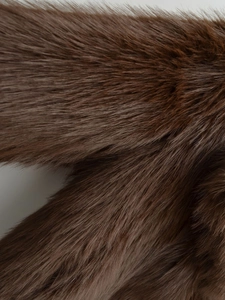 Detailed macro view of dense dark brown faux fur texture with glossy finish and soft touch