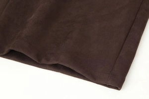 Detailed close-up of dark brown suede fabric texture and professional stitching hem