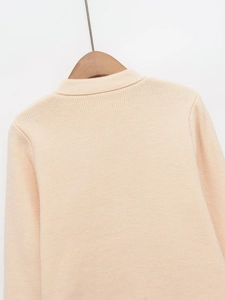 Close-up of beige knit cardigan showing fine texture and neckline on wooden hanger