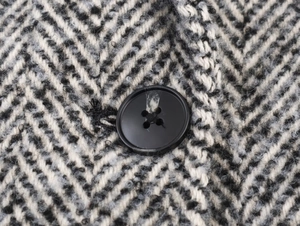 Close-up of black and white herringbone wool fabric with a black button detail