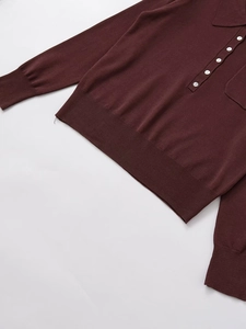 Dettaglio di cinque bottoni bianchi sul colletto polo di questo maglione marrone a maglia