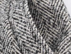 Macro shot of thick black and grey herringbone wool fabric for winter long coats