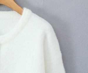Détail du col en tricot pelucheux blanc avec texture douce et col rond pour cette veste
