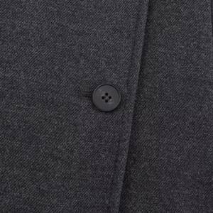Close-up of deep gray wool coat fabric with a classic black four-hole button detail