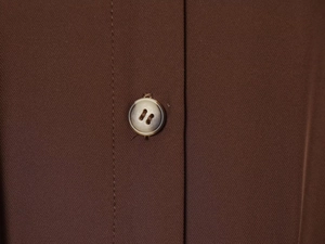 Vue détaillée d'un bouton marbré sur le tissu plissé d'une chemise marron foncé