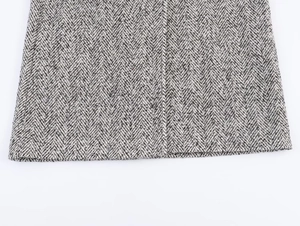 Close-up of classic herringbone pattern on a thick wool-blend double-breasted coat hem