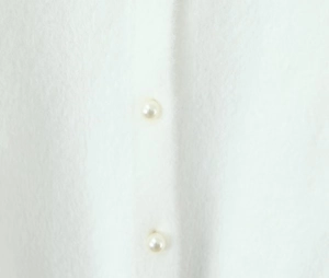 Gros plan du cardigan en maille blanche avec boutons de perles et texture douce