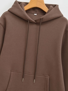 Detailed view of brown drawstring hoodie with kangaroo pocket and rib-knit cuffs on a hanger
